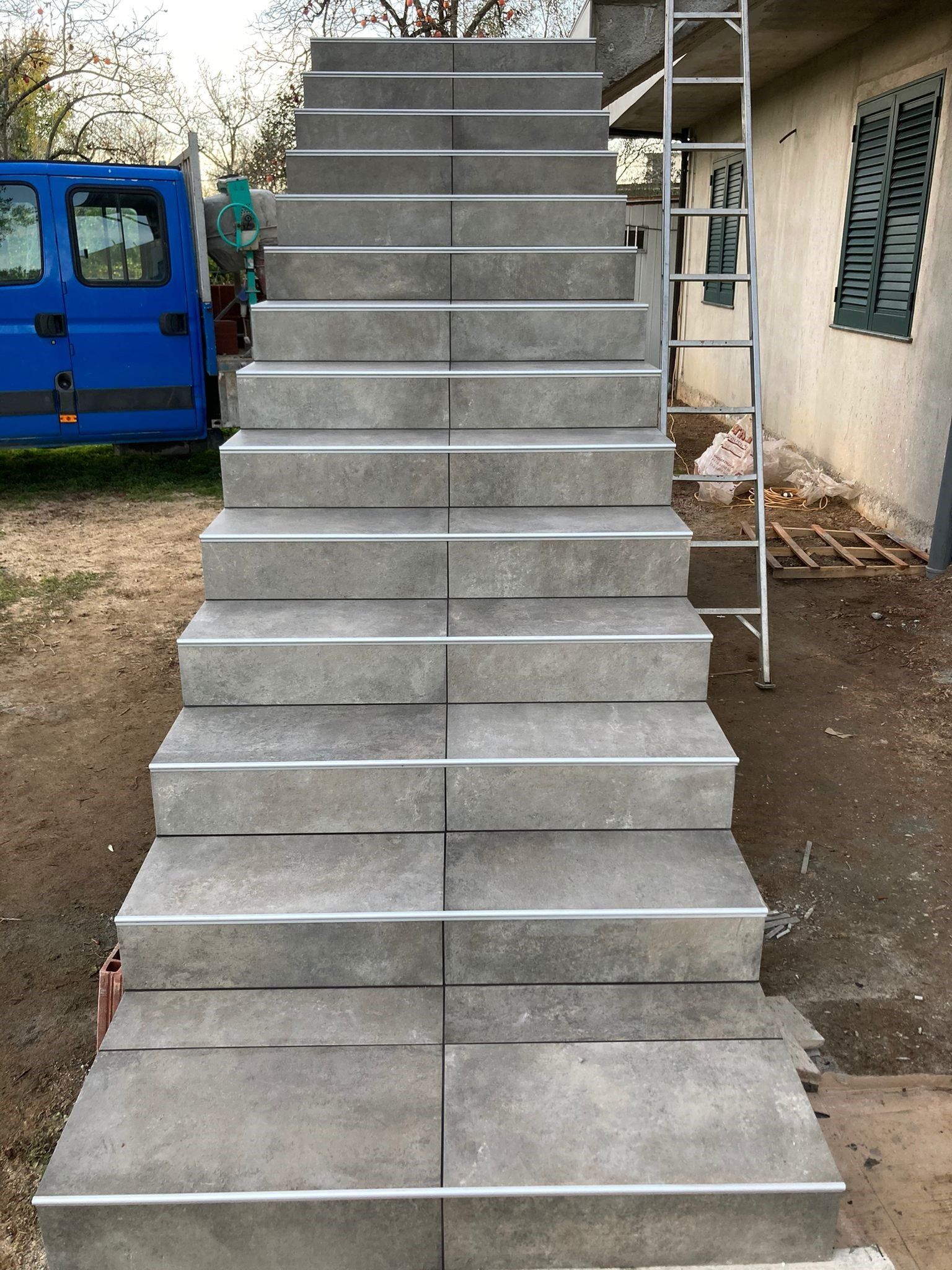 Un furgone blu è parcheggiato dietro una rampa di scale