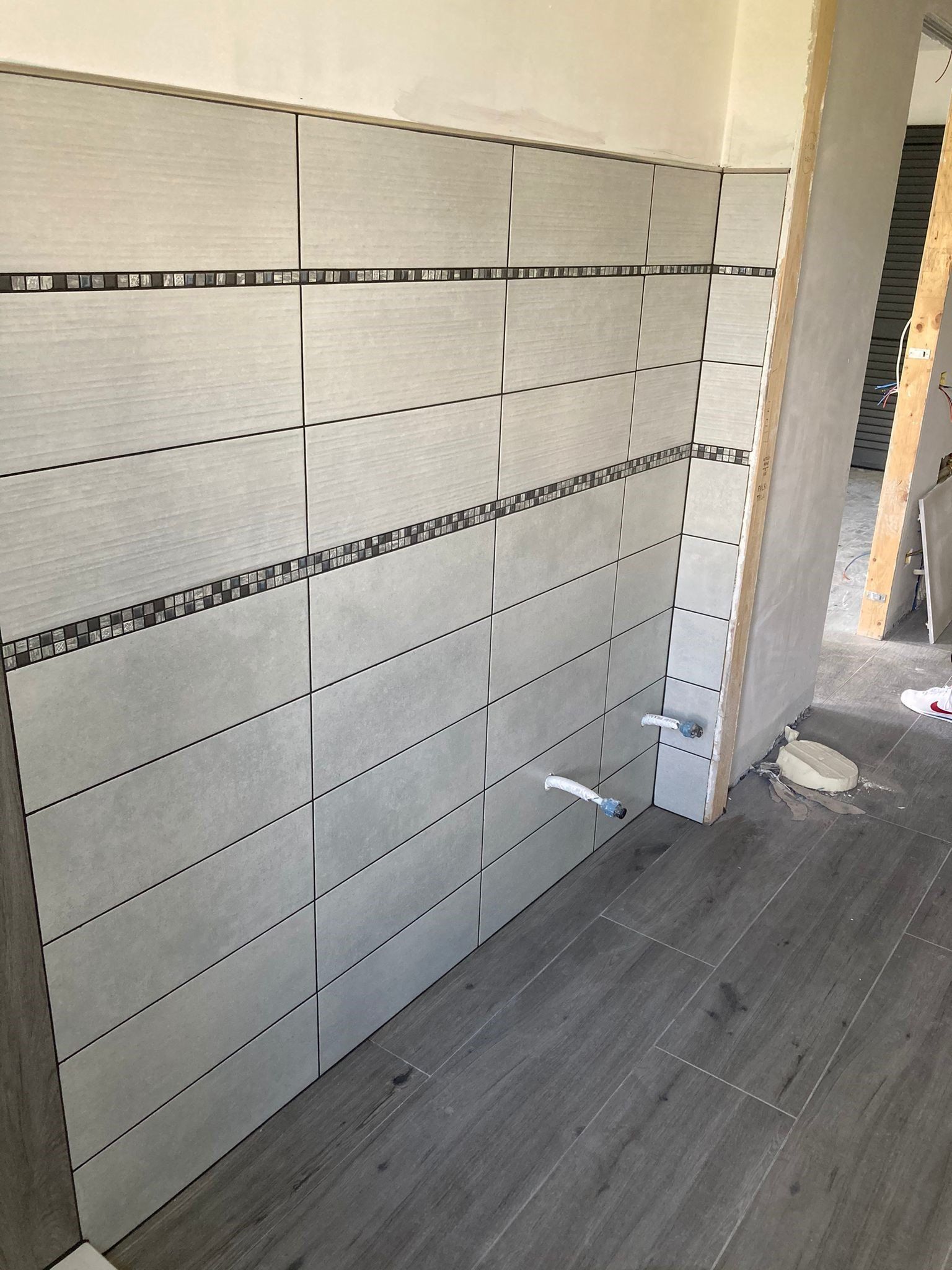 Un bagno in costruzione con piastrelle alle pareti e pavimento in legno.