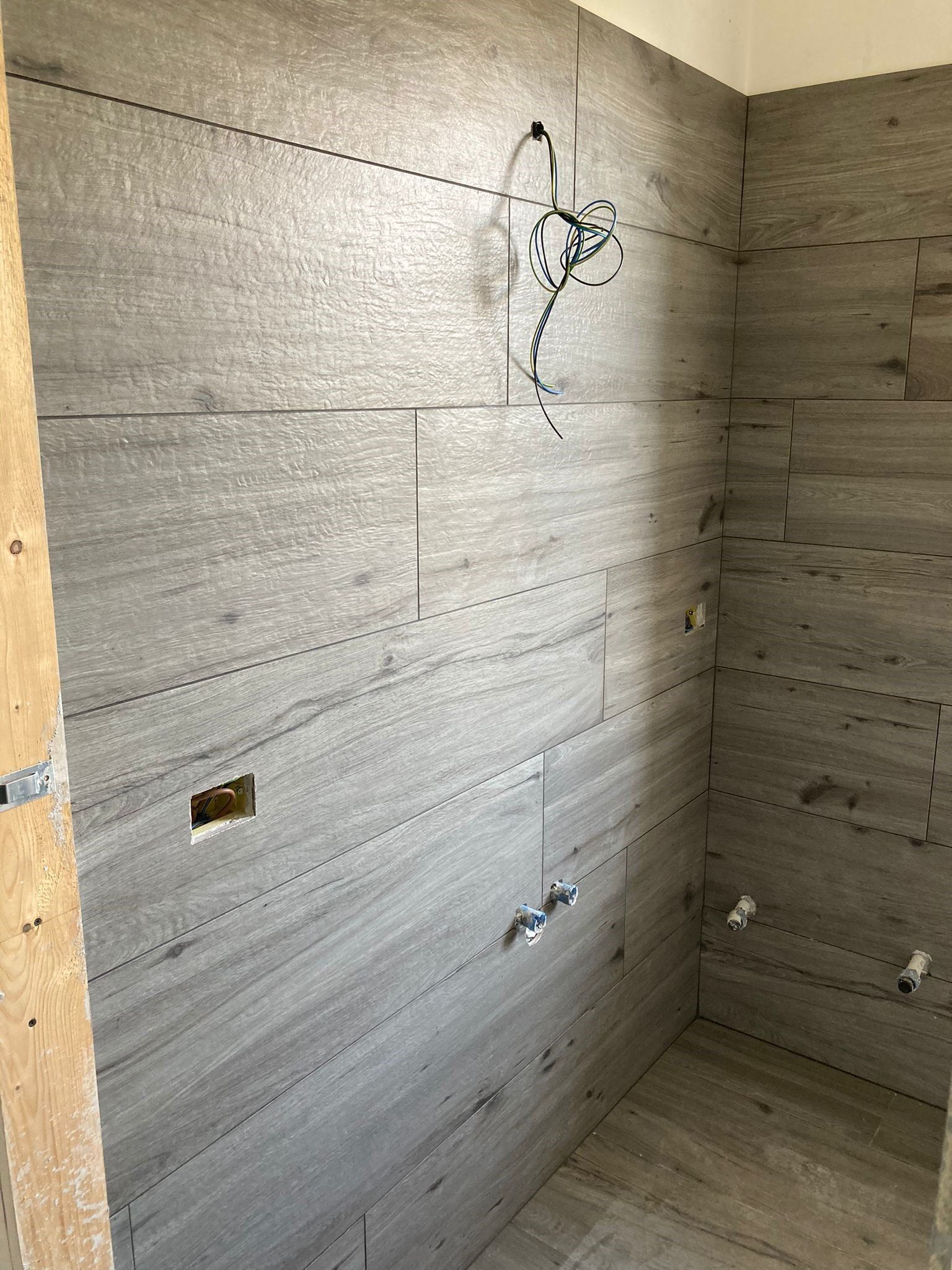 Un bagno con parete in legno e soffione doccia.