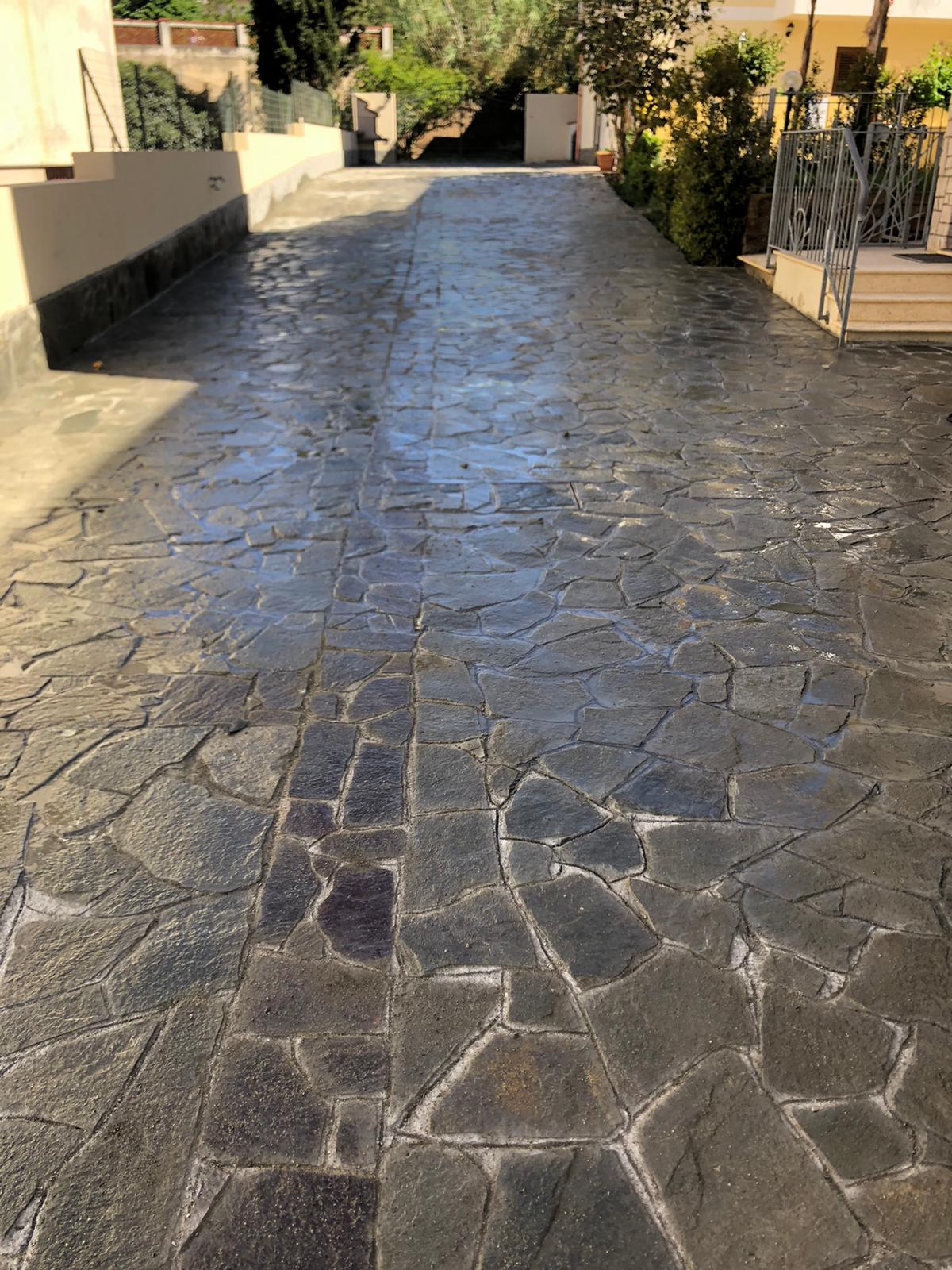 Un vialetto in pietra che conduce a una casa con una recinzione sullo sfondo.