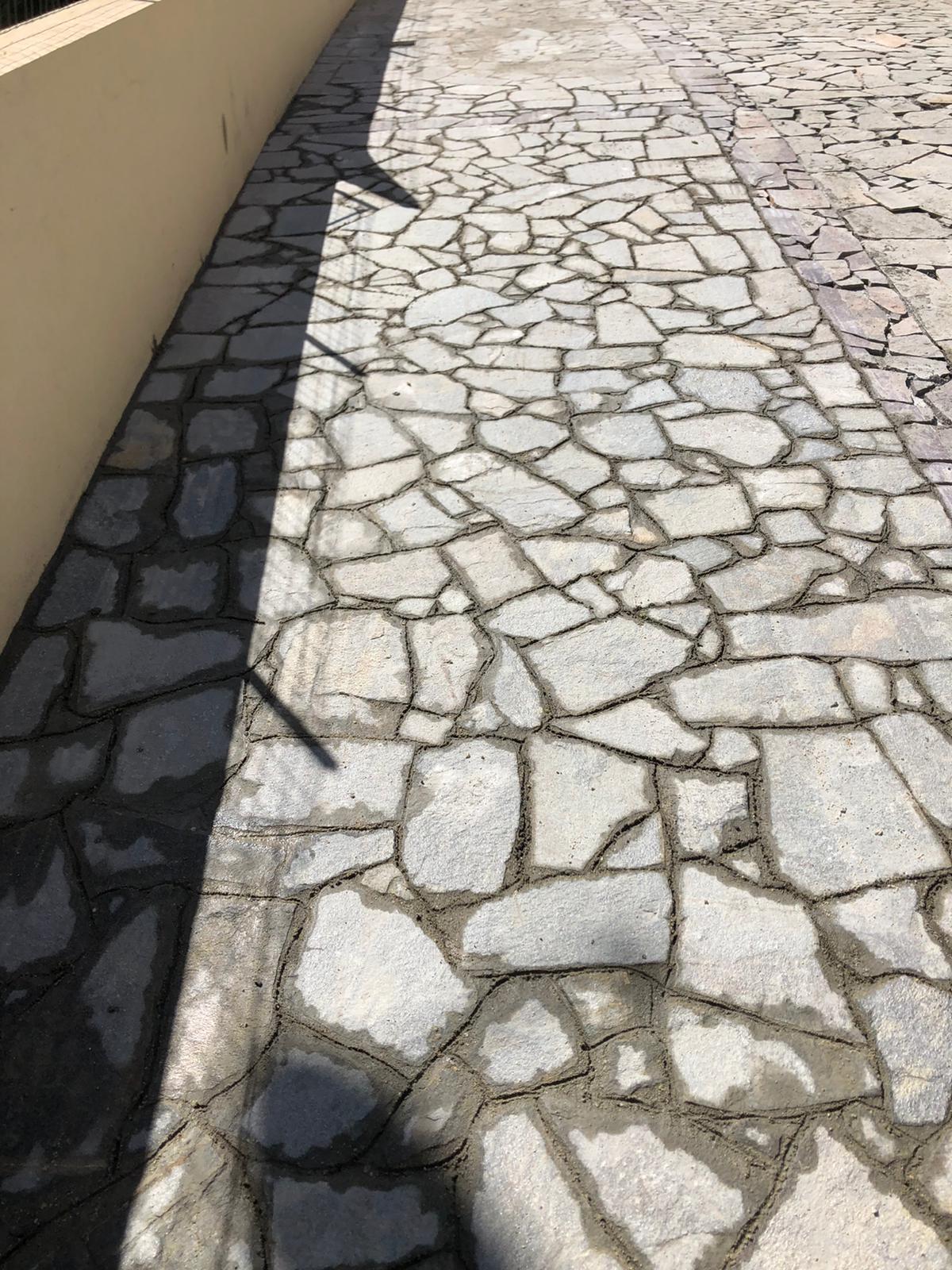 Un marciapiede di pietra con l'ombra di una persona su di esso.