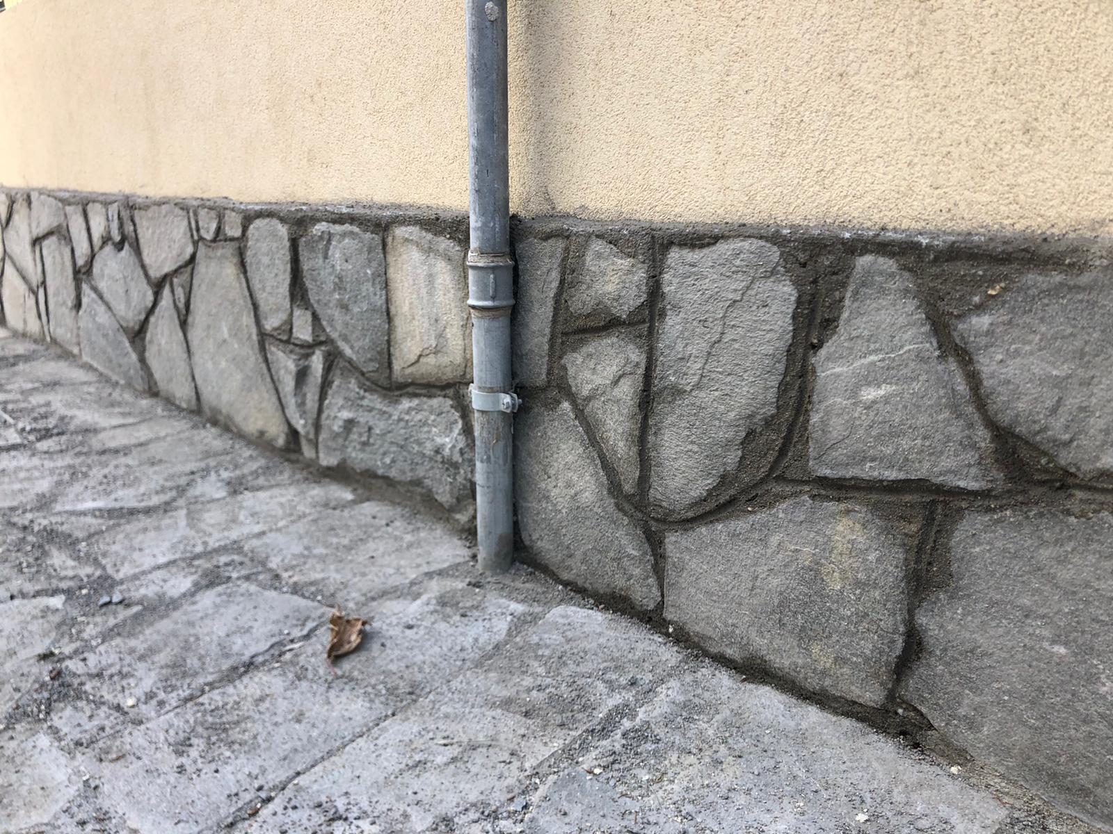 Un muro di pietra con un tubo di scarico su un lato.