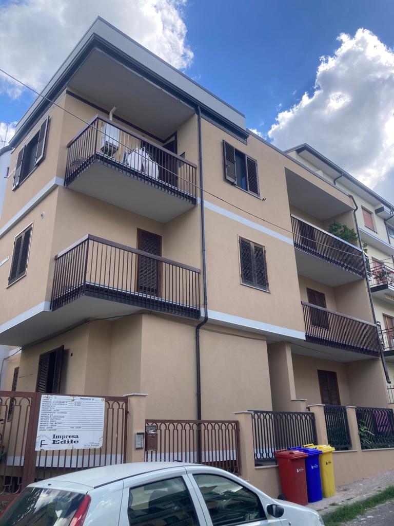 Un'auto bianca è parcheggiata davanti a un palazzo con balconi.