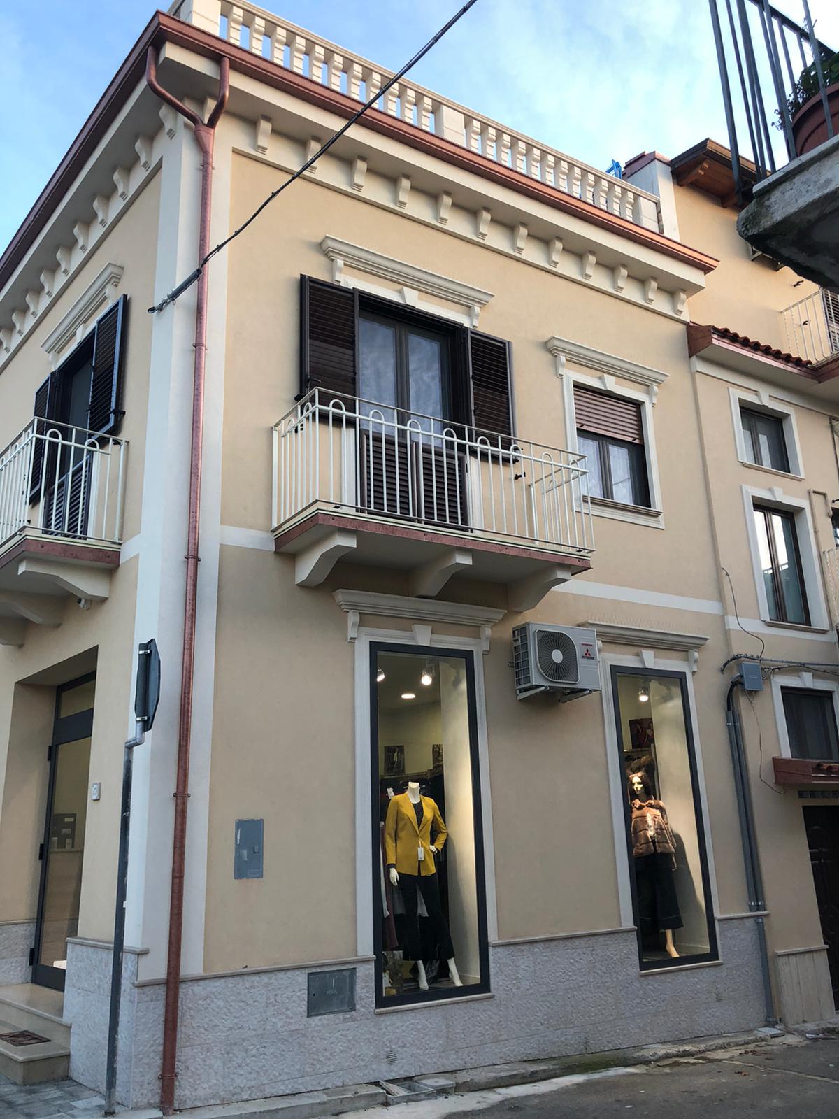 Un edificio con un balcone e un negozio di abbigliamento di fronte.