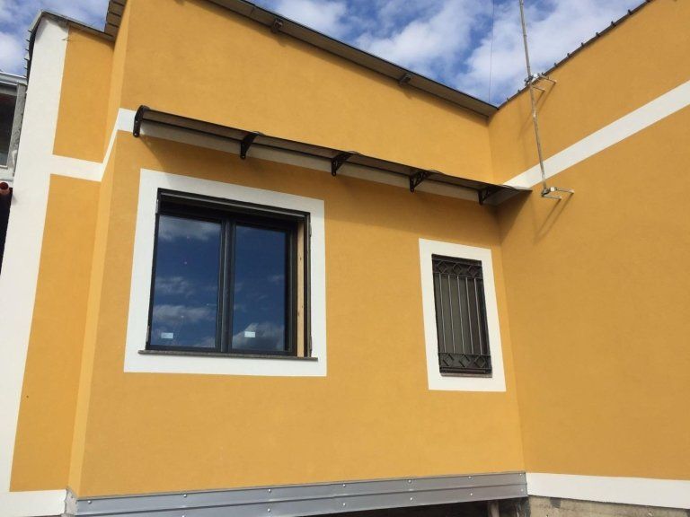 Un edificio giallo con due finestre sul lato