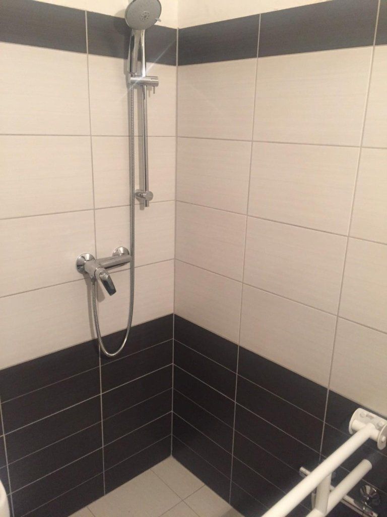 Un bagno con piastrelle bianche e nere e soffione doccia