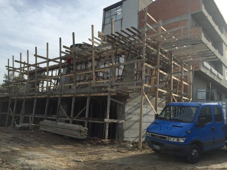 Un furgone blu è parcheggiato davanti a un edificio in costruzione