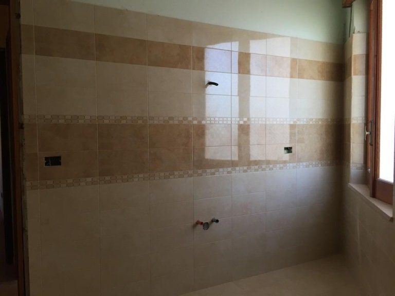 Un bagno con pareti piastrellate e una finestra