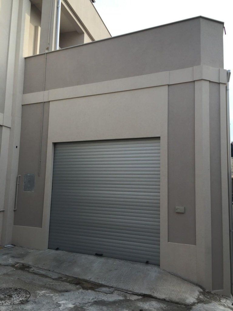 Un grande edificio con una porta da garage grigia