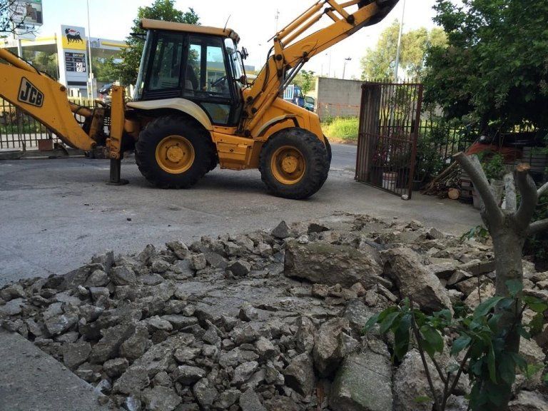Un bulldozer giallo JCB sta lavorando su un mucchio di rocce