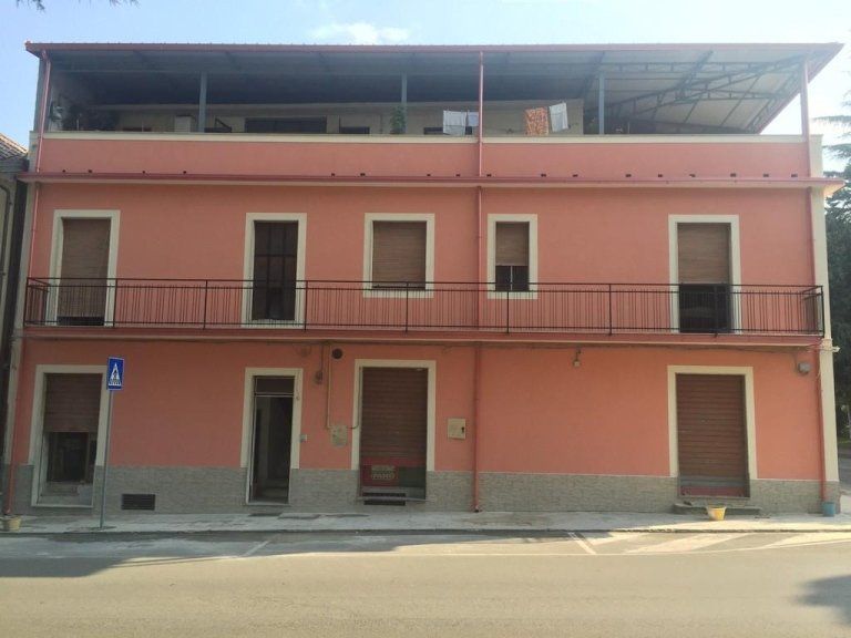 Un grande edificio rosa con balconi e persiane alle finestre