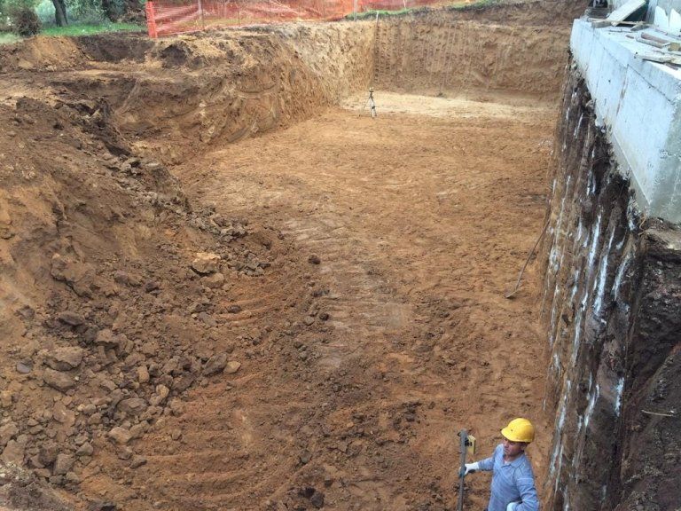 Un operaio edile è in piedi in un grande mucchio di terra.