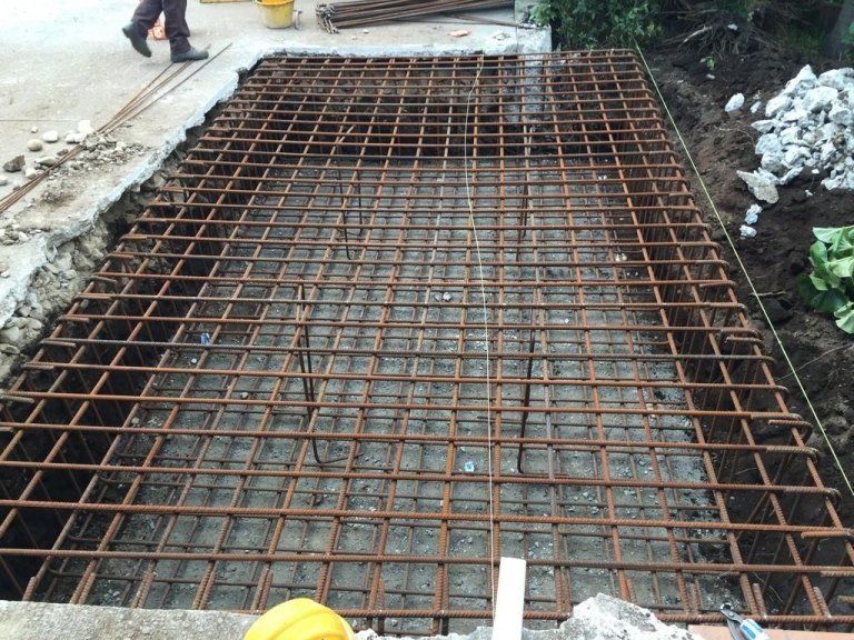 Una persona che indossa un casco giallo è in piedi accanto a una grande griglia metallica