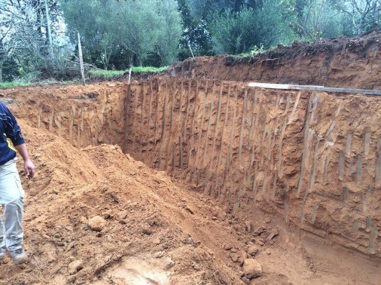 Un uomo è in piedi davanti a un grande mucchio di terra.