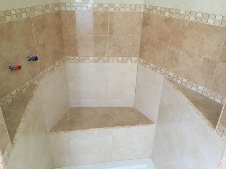 Una cabina doccia con panca e scaffali in un bagno.