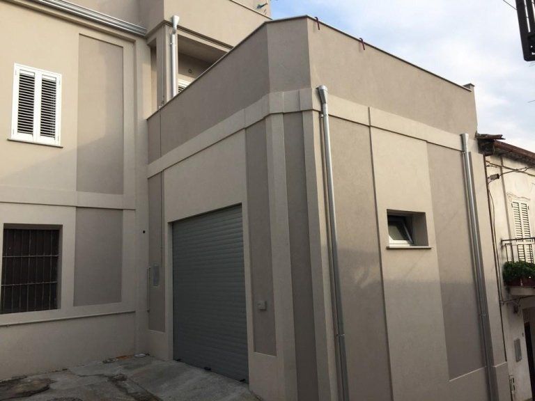 Un edificio con una porta da garage grigia e due finestre