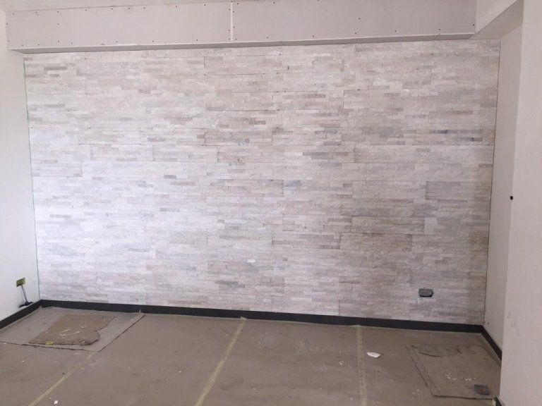 Una stanza vuota con un muro di mattoni bianchi e un pavimento in legno.