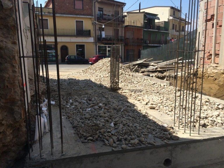 Un mucchio di ghiaia si trova di fronte a un edificio in costruzione.