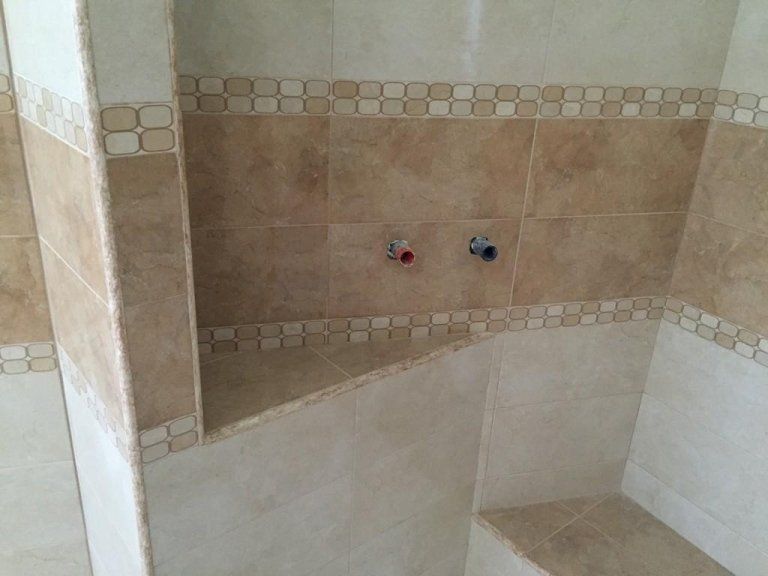 Una cabina doccia con una mensola e piastrelle sul muro.