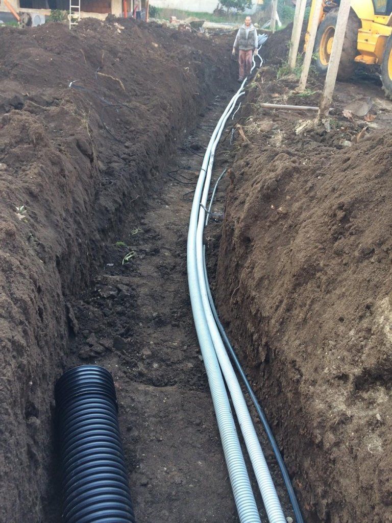 Un uomo è in piedi in una trincea accanto a un grande tubo.