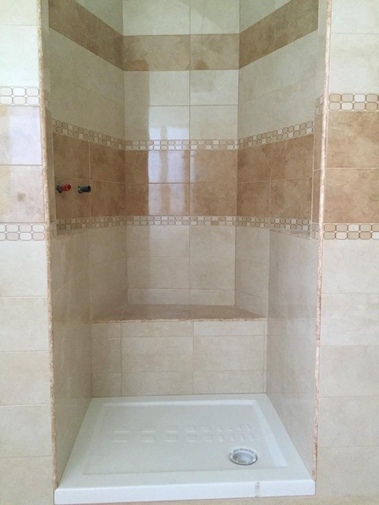 Un bagno con cabina doccia e pareti piastrellate.