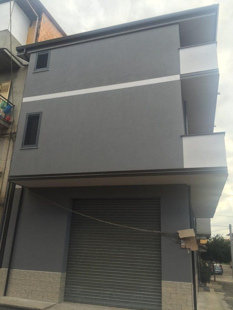 Un edificio con un portone da garage e un balcone su un lato.