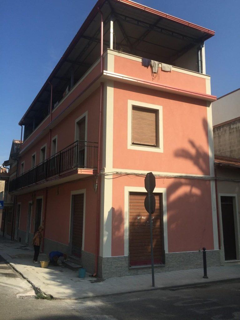 Un edificio rosa con un balcone in cima