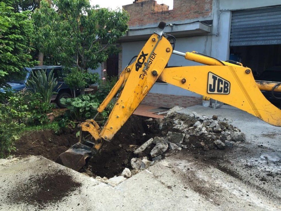 Un escavatore JCB giallo sta scavando una buca nel terreno