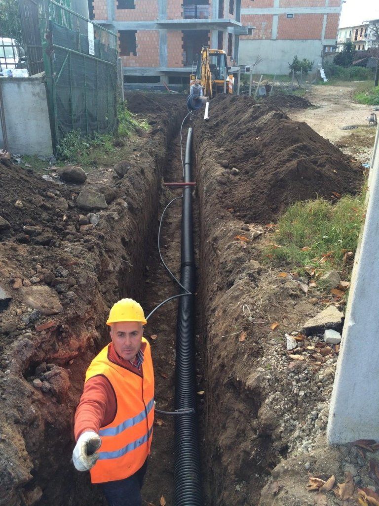 Un operaio edile è in piedi in una trincea accanto a un tubo.