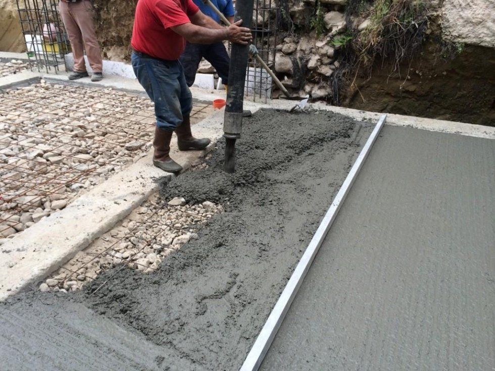 Due uomini stanno versando cemento su un marciapiede.