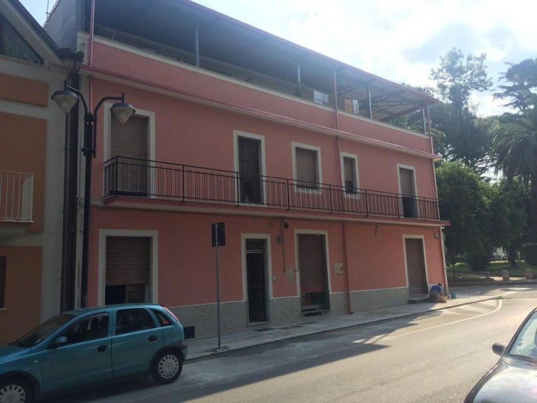 Un'auto blu è parcheggiata davanti a un edificio rosa.