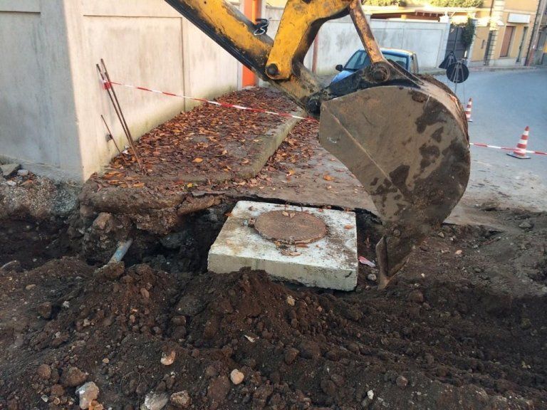 Un escavatore giallo sta scavando una buca nel terreno