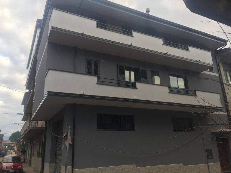 Un grande edificio con un'auto rossa parcheggiata di fronte