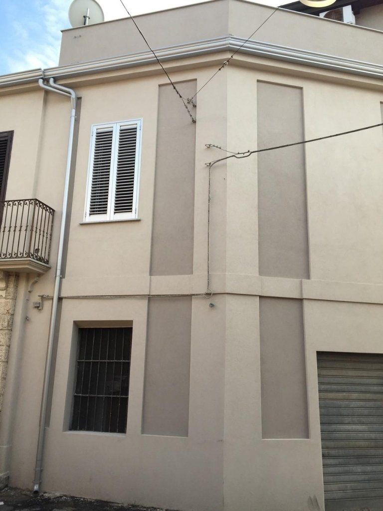 Un edificio con un balcone e persiane alle finestre