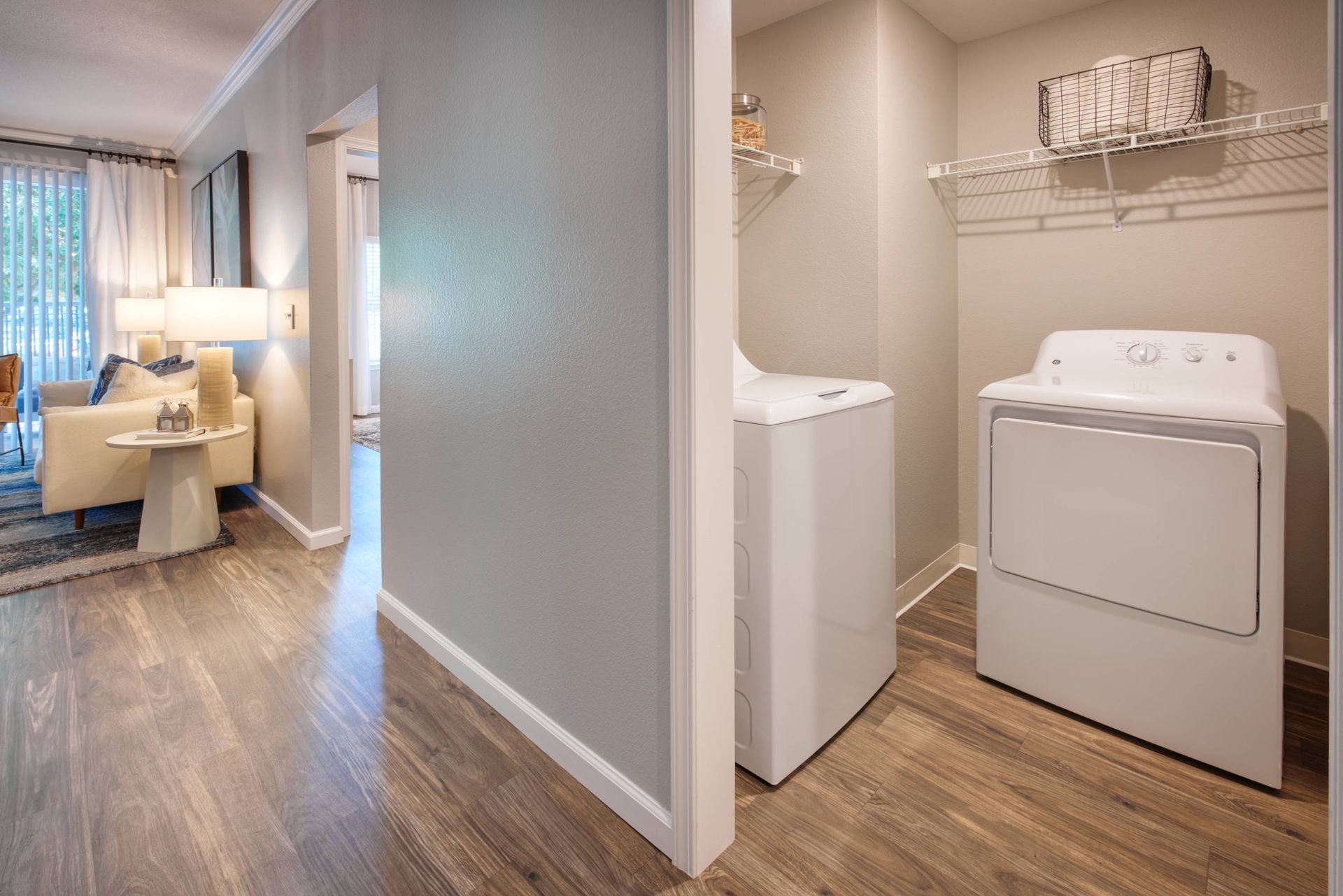 Living area with sofa and lamp on the left; laundry closet with washer and dryer on the right.