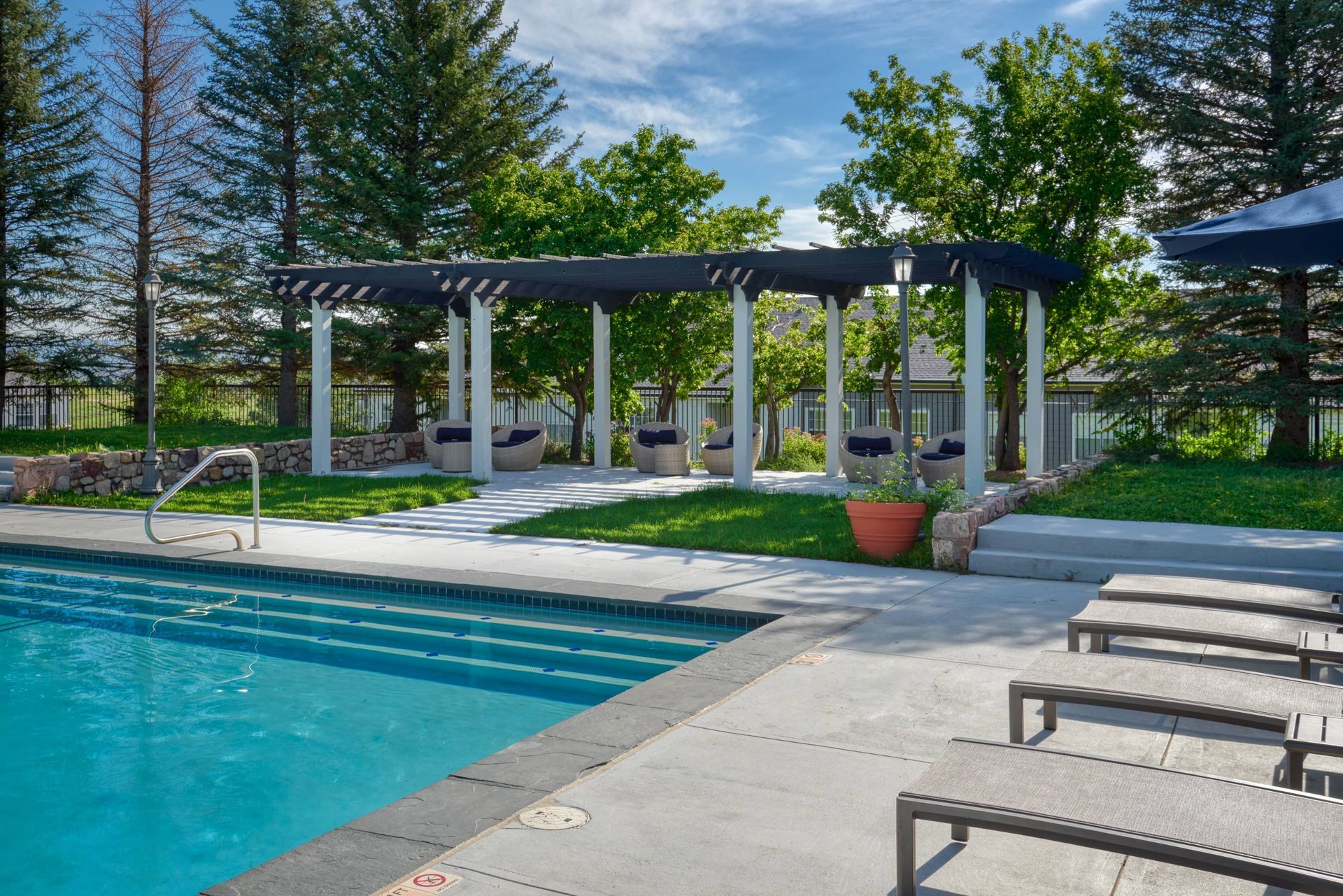 Outdoor pool area with a covered seating pergola and lounge chairs.