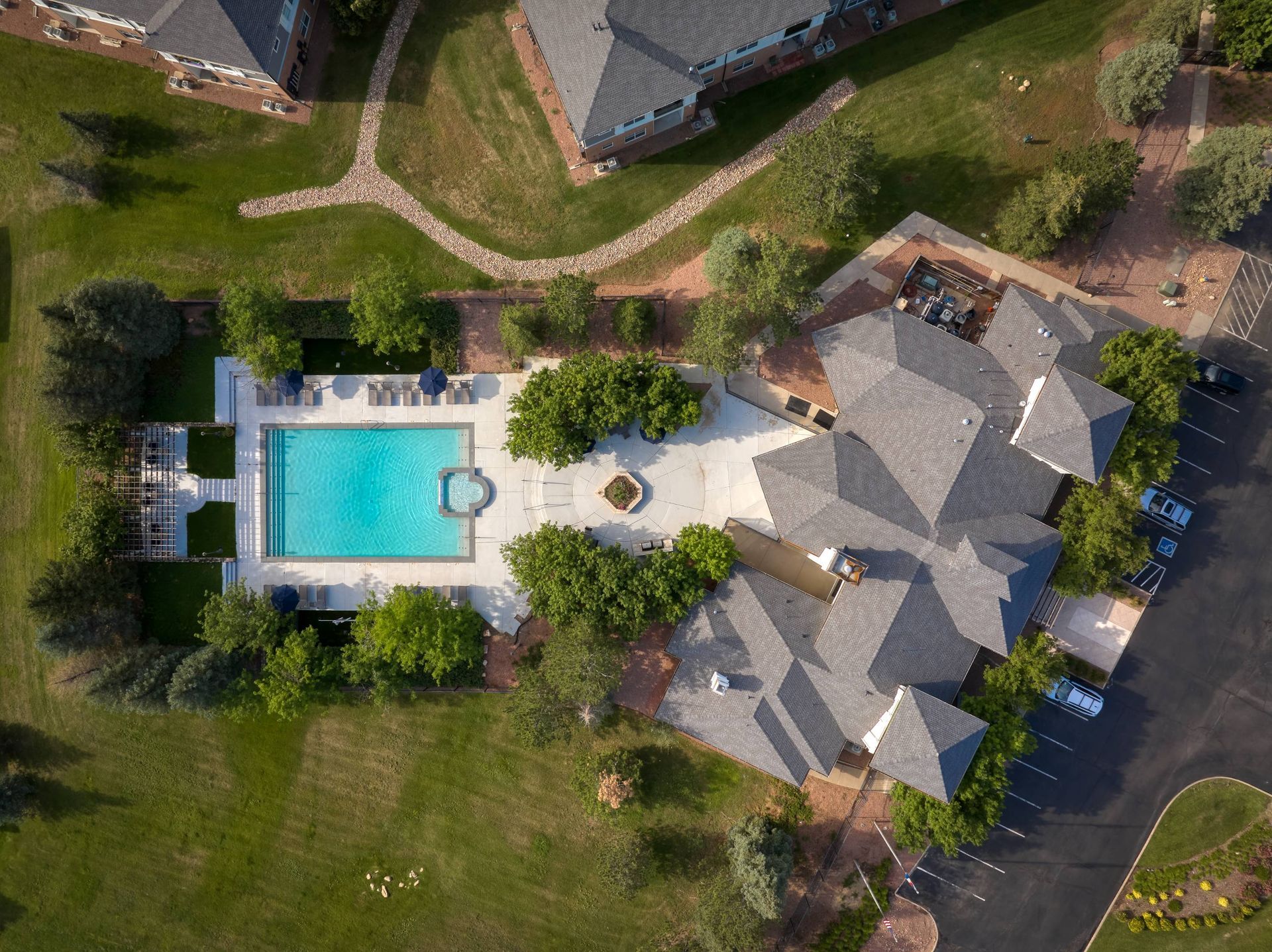 Aerial view of an apartment community pool surrounded by buildings and green space.