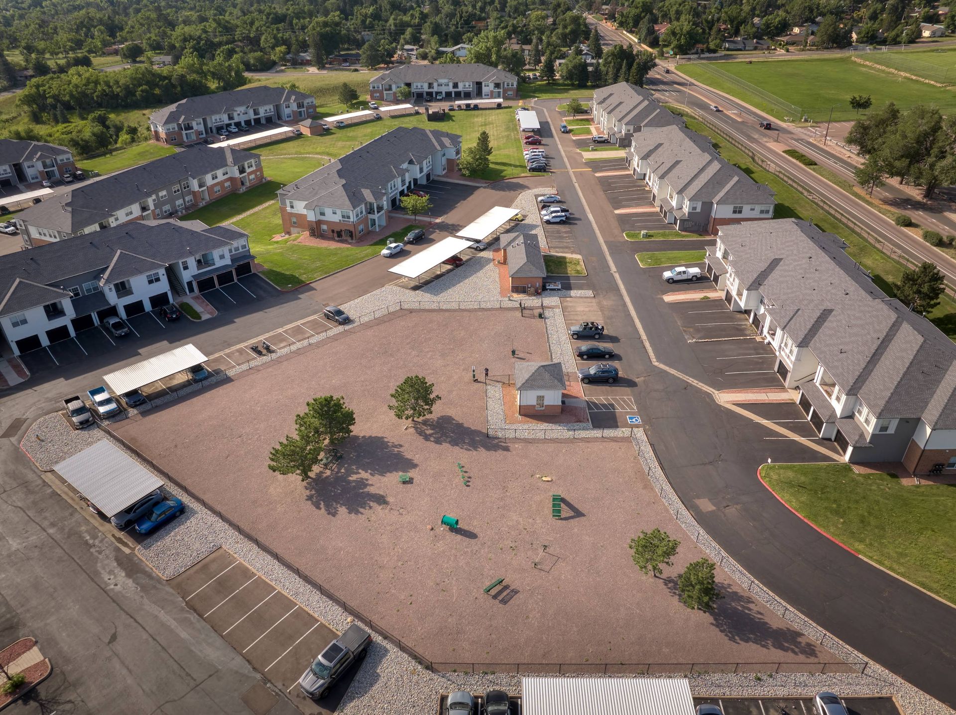 Bird's-eye view of a multifamily property with apartment buildings framing a central open yard, plus parking and drive aisles.