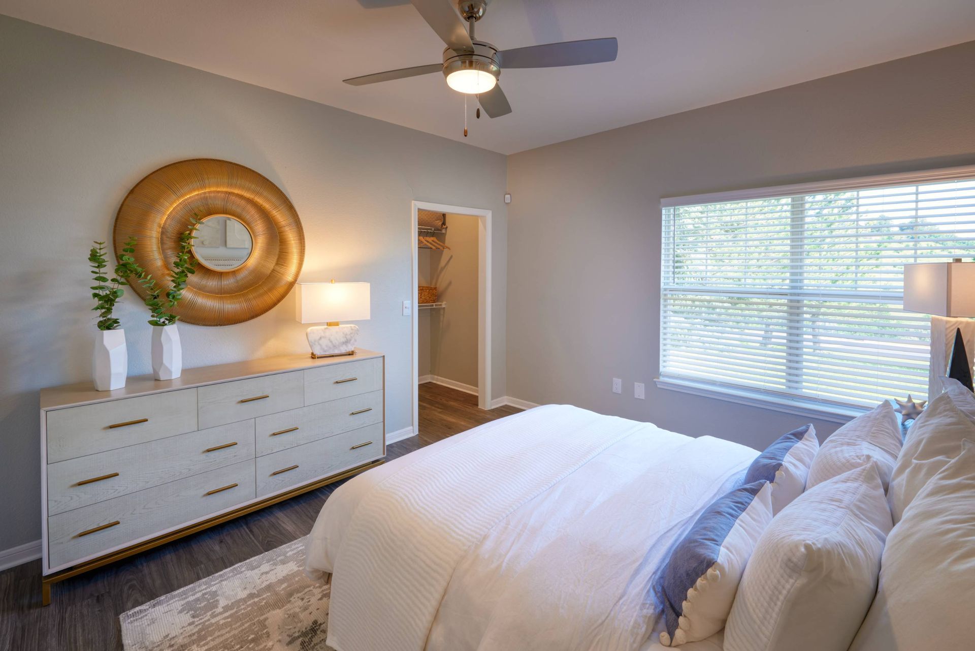 Bedroom with a bed, dresser with circular woven wall art, and an open closet.