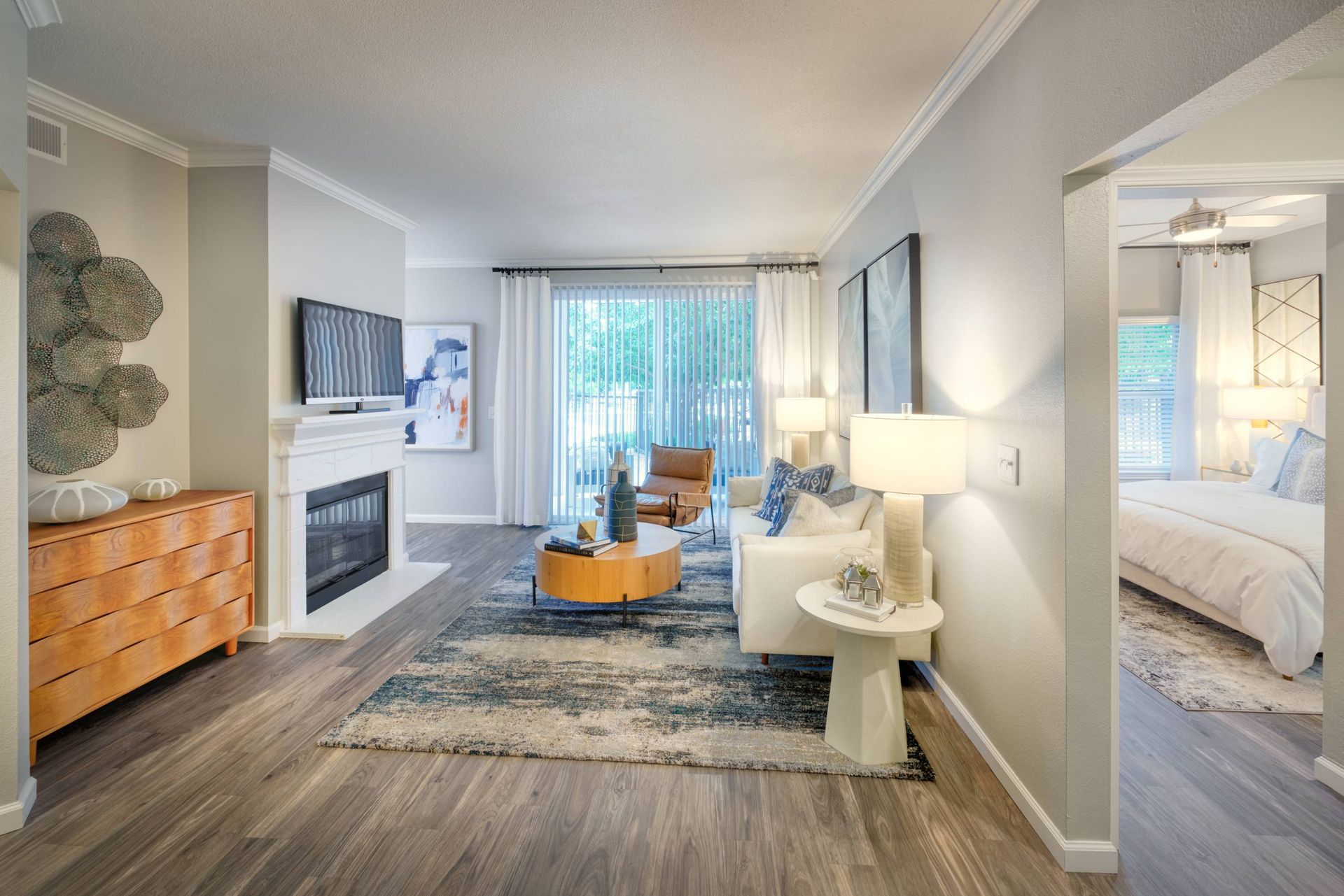 Living room in an apartment with a sofa, coffee table, fireplace, TV, and sliding glass doors.