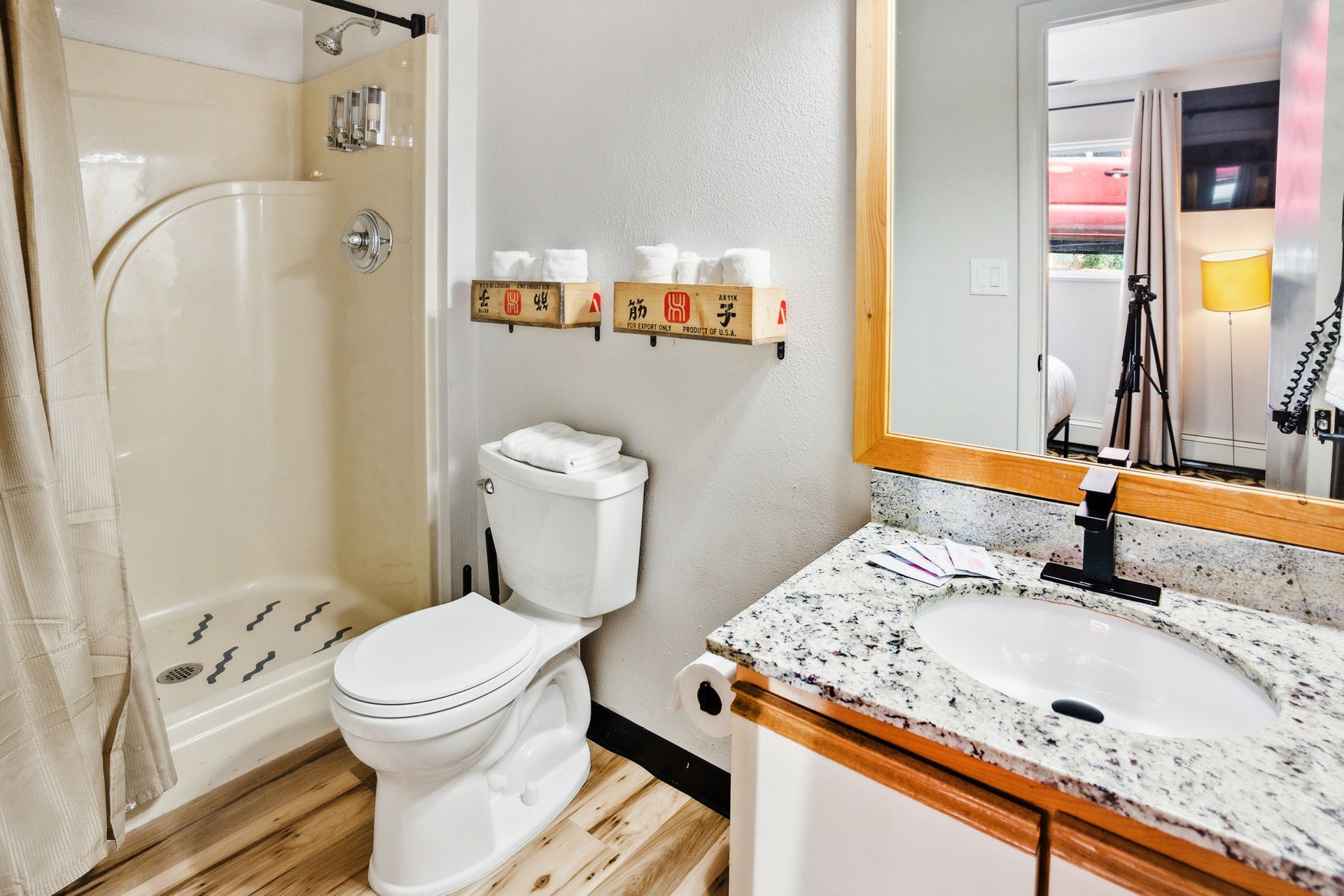 A bathroom with a toilet , sink , shower and mirror.