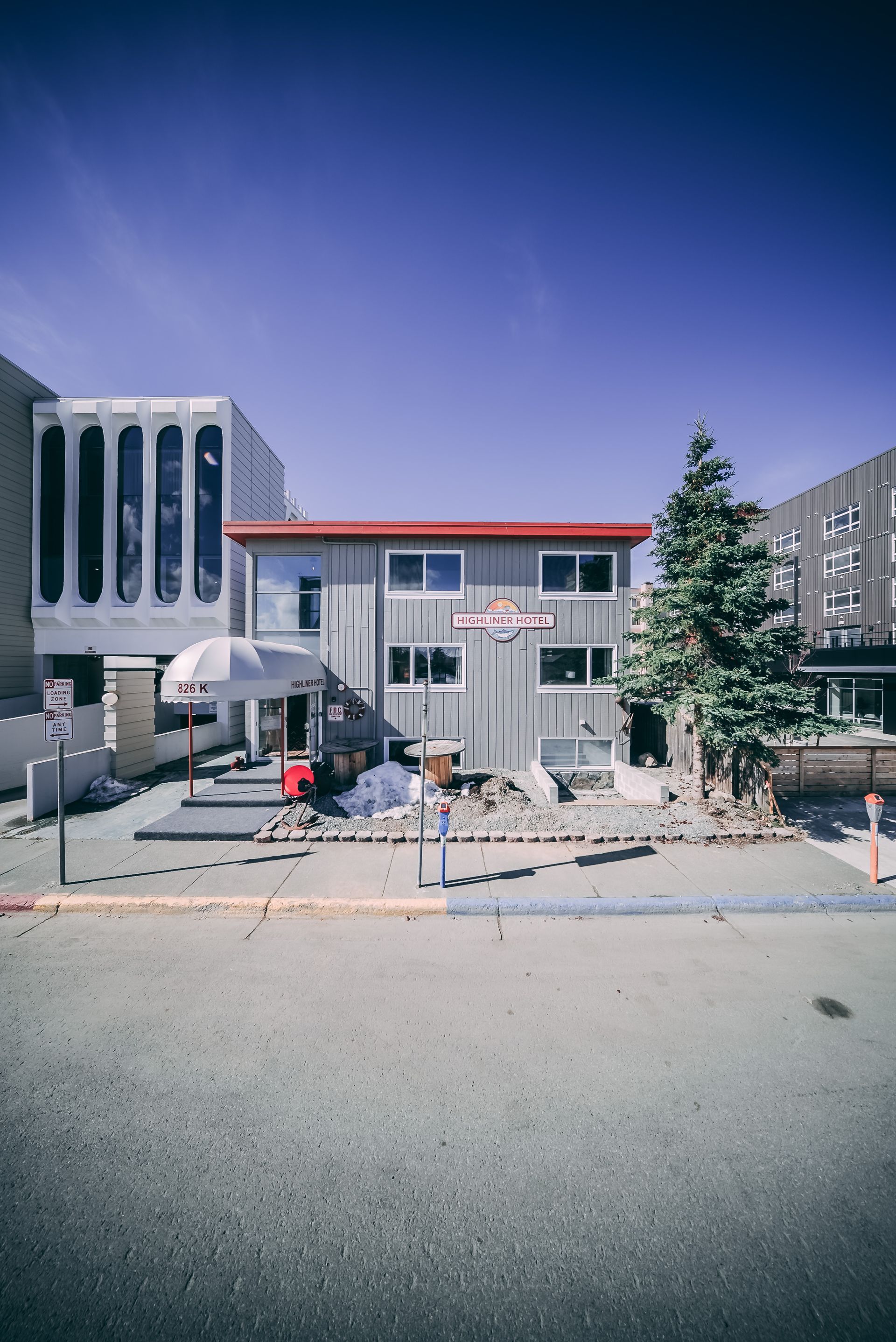A large gray building with a red roof is sitting in the middle of a city.