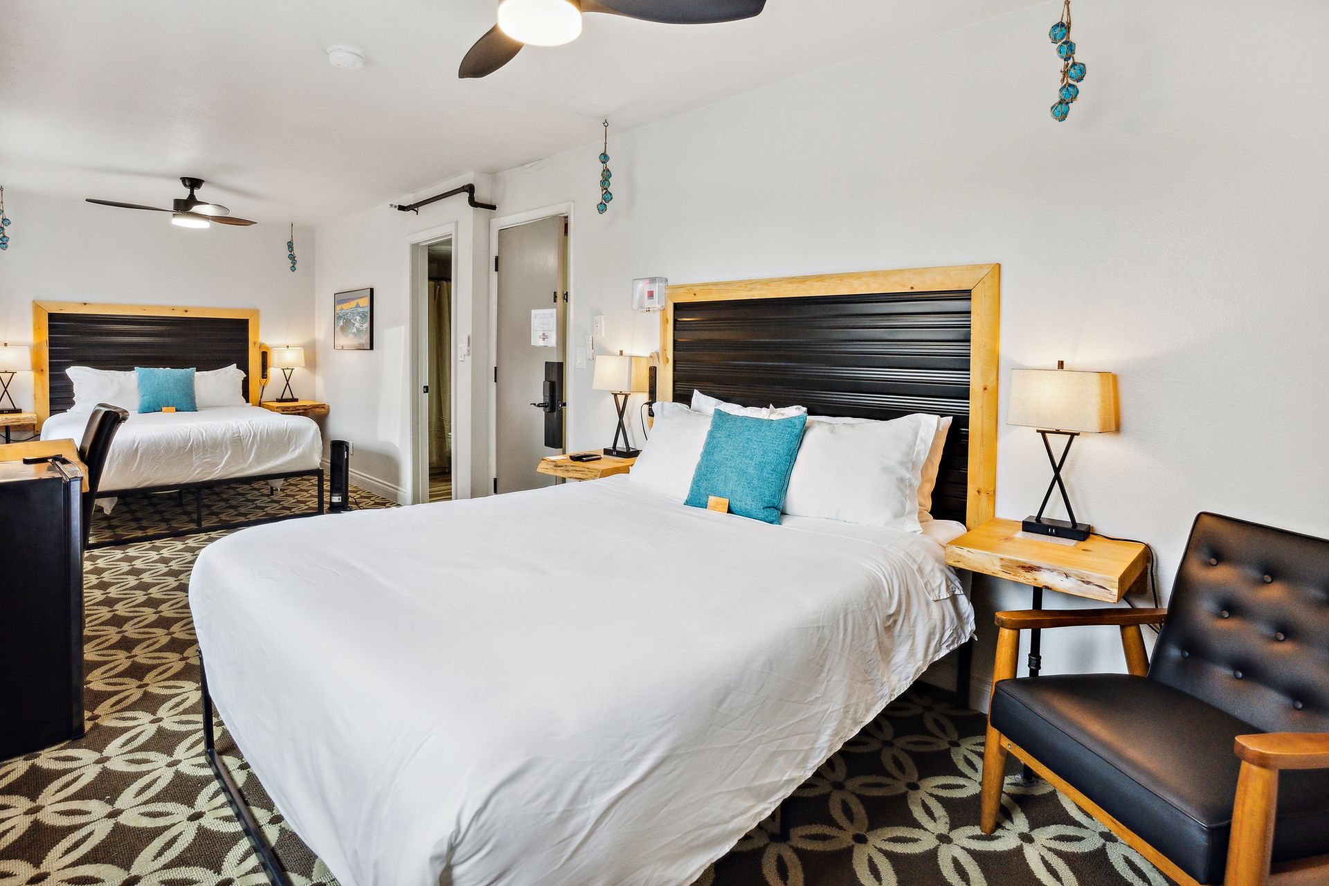 A hotel room with two beds , a chair and a ceiling fan.