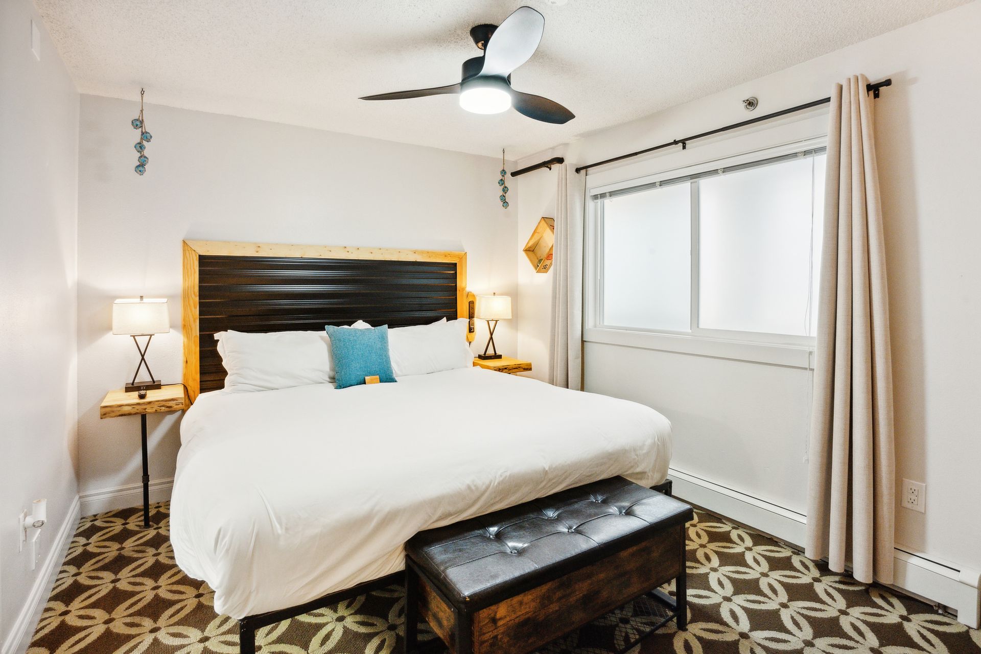 A hotel room with a king size bed and a ceiling fan.