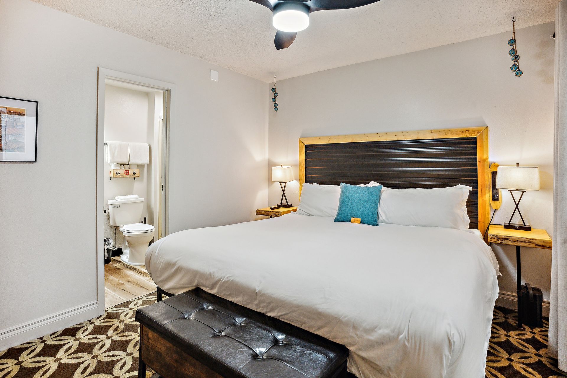 A hotel room with a king size bed and a ceiling fan.