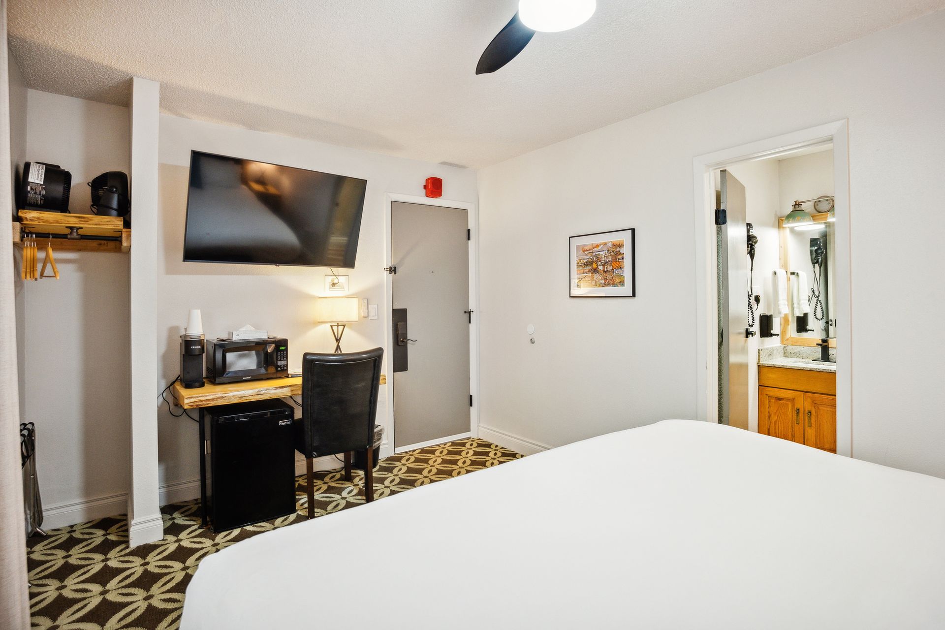 A hotel room with a bed , desk , chair and television.