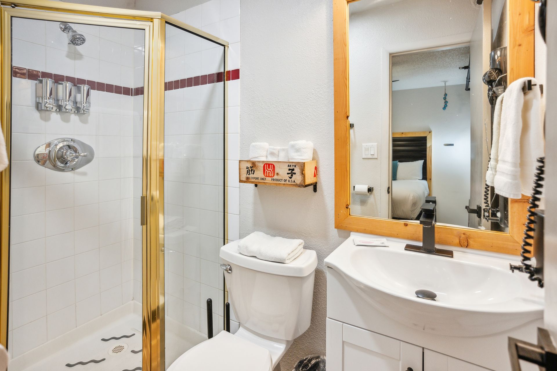 A bathroom with a toilet , sink , shower and mirror.