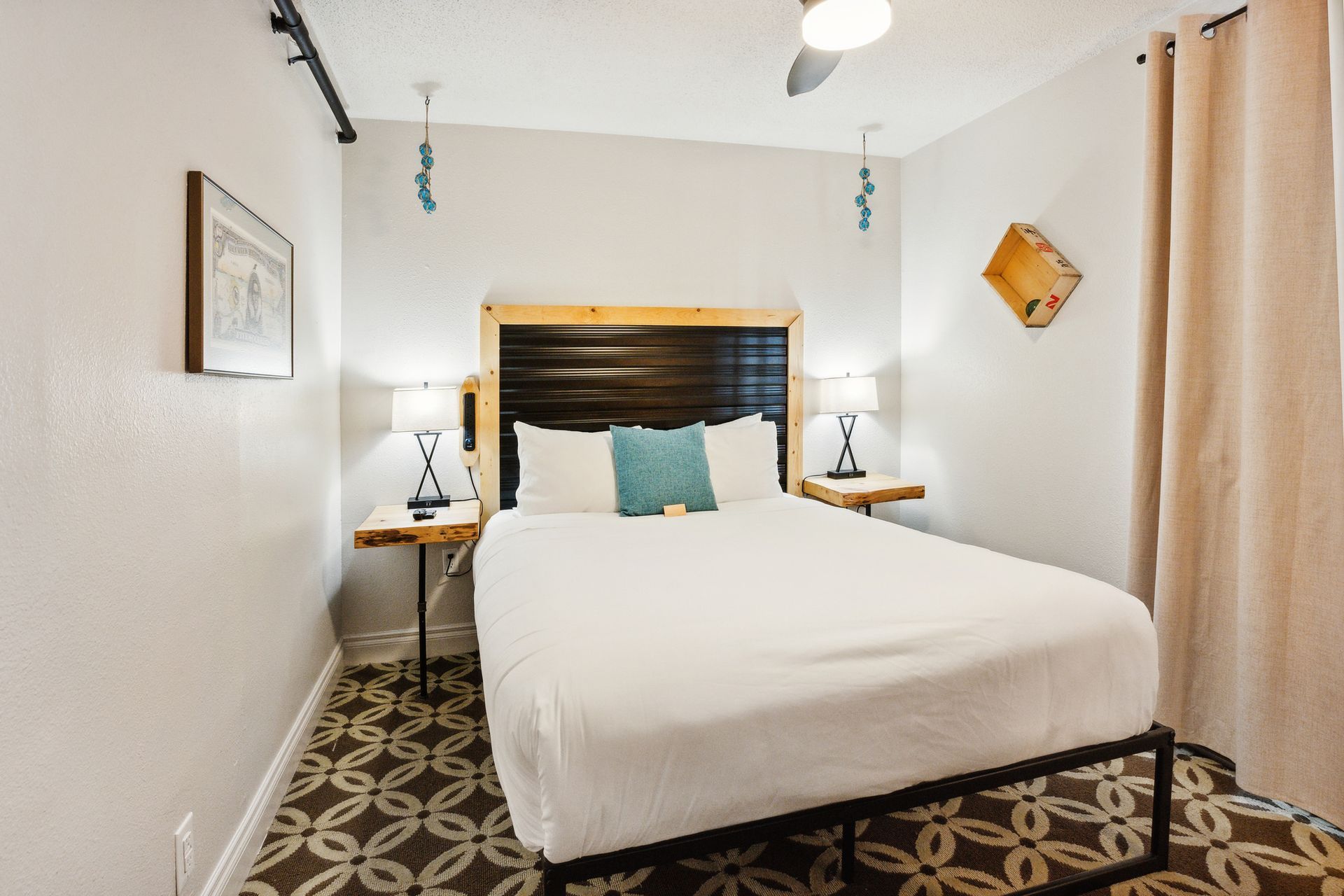 A hotel room with a king size bed and a ceiling fan.