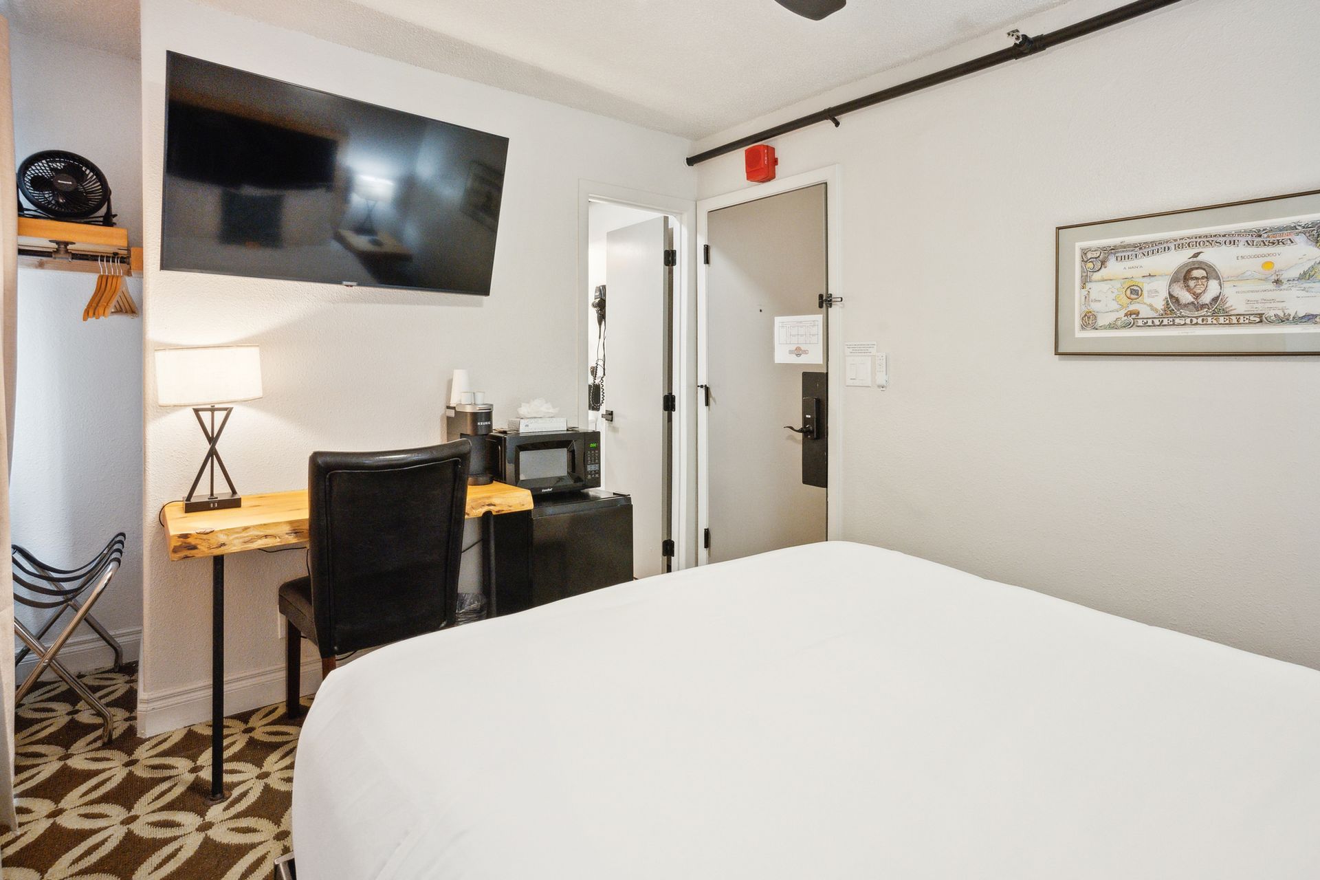 A hotel room with a bed , desk , chair and television.