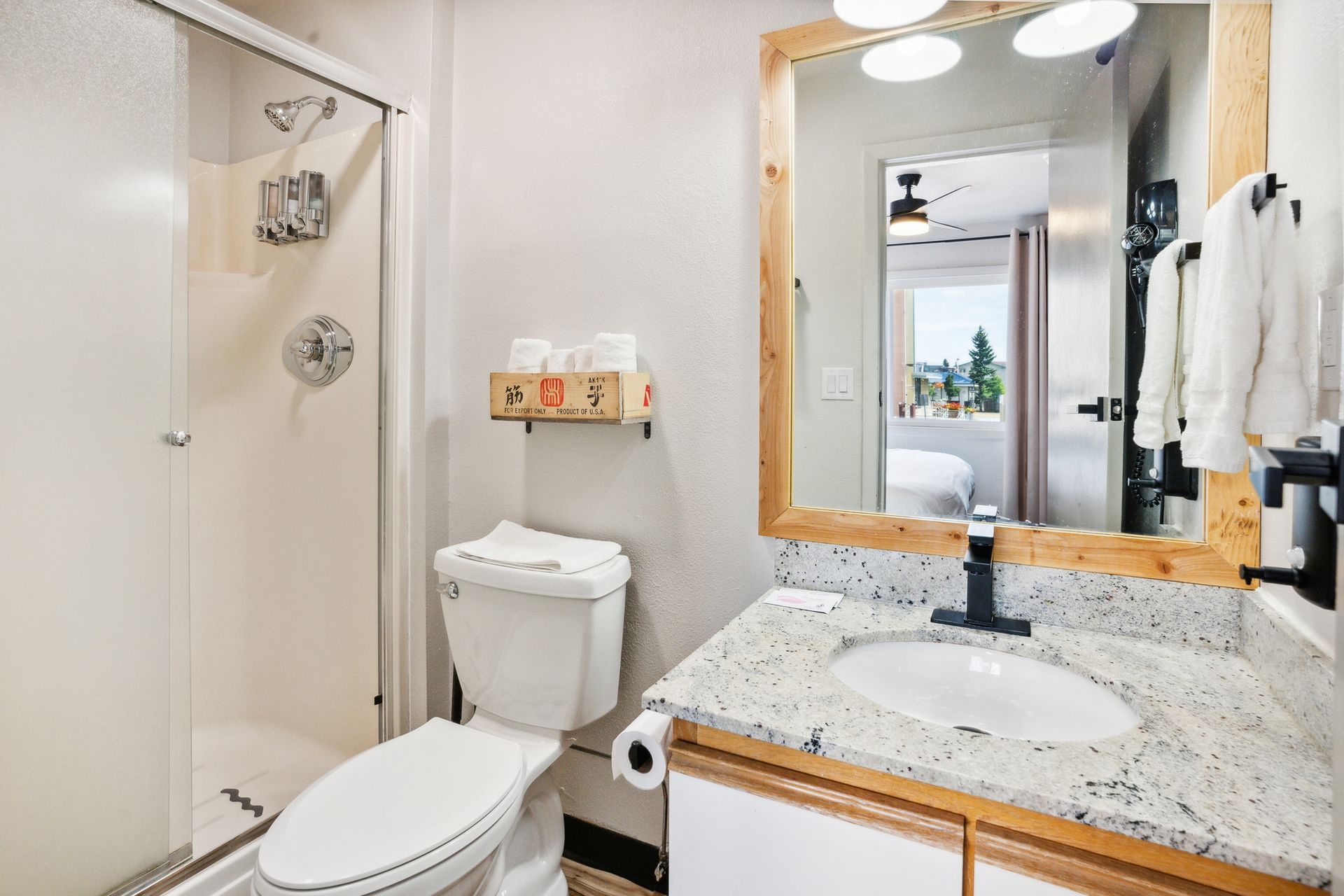 A bathroom with a toilet , sink , mirror and shower.